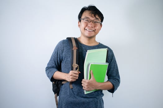 Asian young male student wearing bag and carrying books smiling and happy expression with isolated white background photo