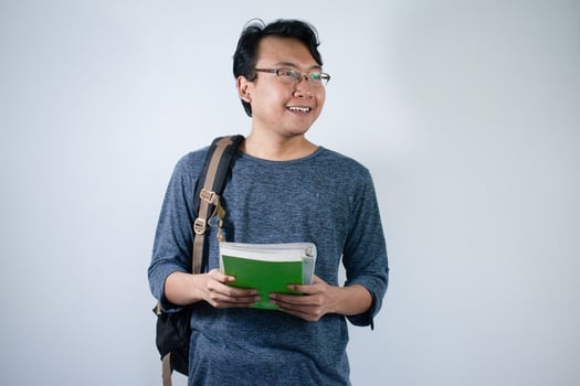 Asian young male student wearing bag and carrying books smiling and happy expression with isolated white background photo