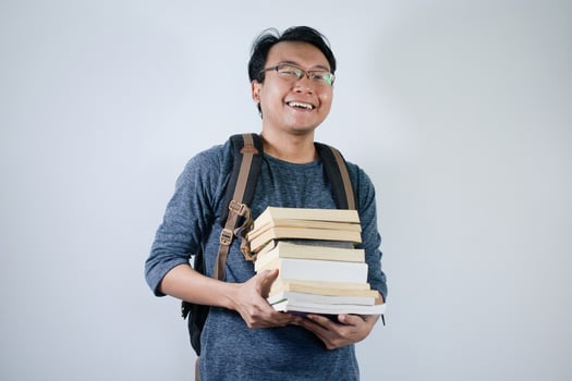 Asian young male student wearing bag and carrying a lot of books smiling and happy expression with isolated white background photo