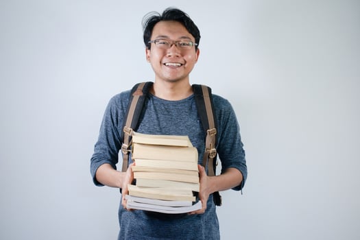 Asian young male student wearing bag and carrying a lot of books smiling and happy expression with isolated white background photo