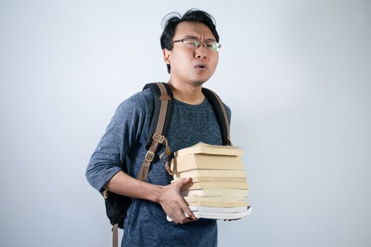 Asian young male student wearing bag and carrying a lot of books smiling and happy expression with isolated white background photo