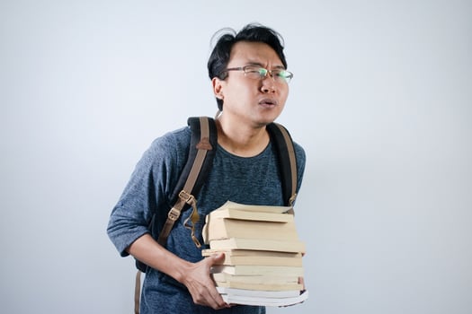 Asian young male student wearing bag and carrying a lot of books smiling and happy expression with isolated white background photo