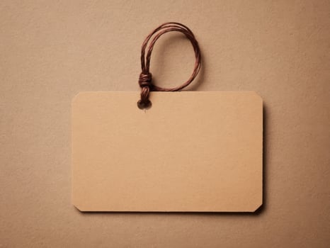 Brown Paper Price Tag With String Isolated on brown background. photo