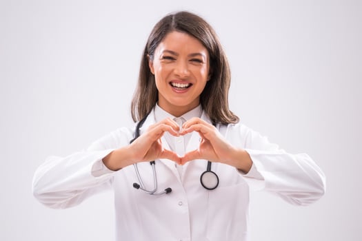 Portrait of doctor who is cheerful and showing heart shape with hands. photo