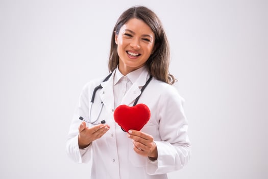 Portrait of happy doctor who is showing heart shape pillow. photo