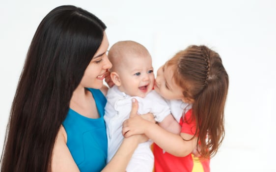 Happy mother and cute little kids spending time together and smiling at camera photo