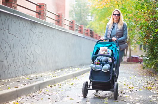 Young blond woman with stroller going for a walk in a park photo