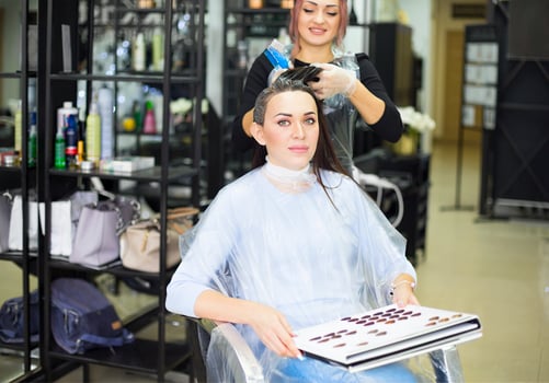 Gorgeous happy woman looking to the camera while examining hair dye color chart with her hairdresser at the beauty salon treatment photo