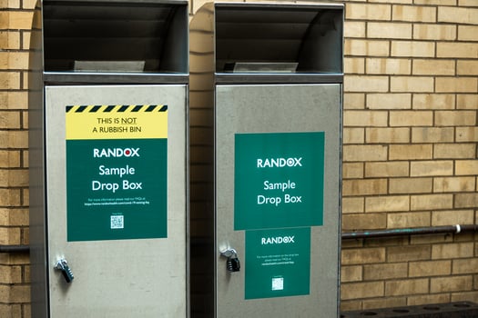 London, UK. september 20, 2022. Coronavirus sample drop box of Randox on city street next to fire service center and potted plant photo