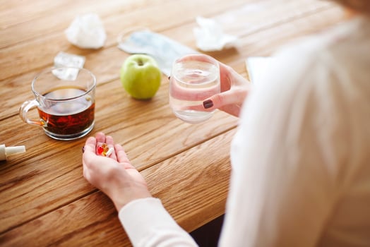 Crop woman taking pills at table photo