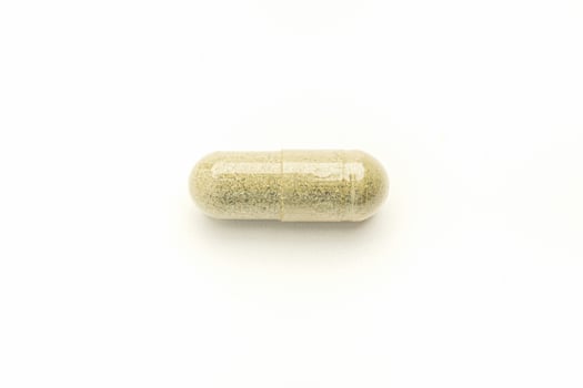 Close-up of Andrographis paniculata capsule placed isolated on white background. Space for text. Herbal, medicine, and healthcare concept photo