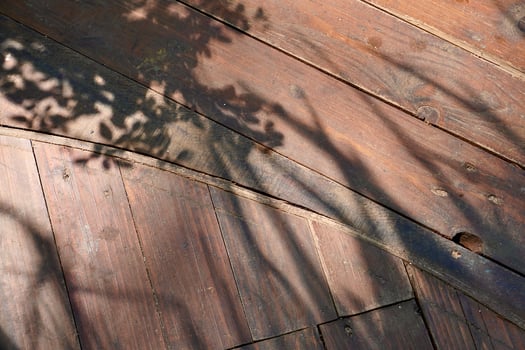 Tree and plants shadow on brown wooden flooring surface isolated on horizontal ratio background. photo