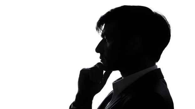 Silhouette side pose of asian businessman with suit and hand touch chin in shadow against white background. concept of business leadership, thinking, decision photo