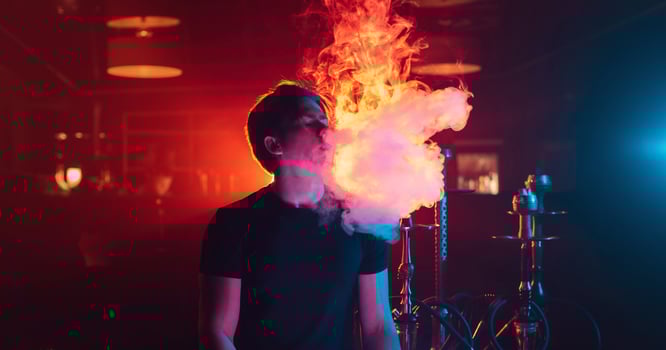 man is relaxing and Smoking a hookah and blowing a cloud of smoke in a lounge cafe photo