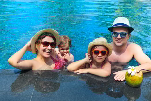 Happy young family with little kids having fun together in the pool photo
