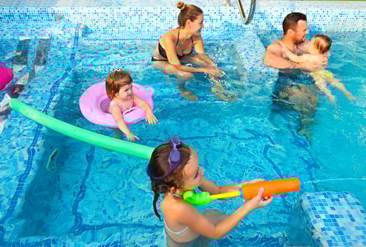 Happy young family with little kids in the pool photo