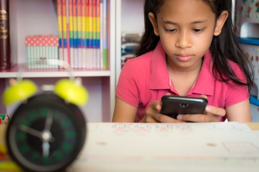 Little girl using mobile phone with wireless internet at home. Education concept. photo
