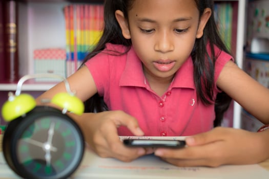 Little girl using mobile phone with wireless internet at home. Education concept. photo