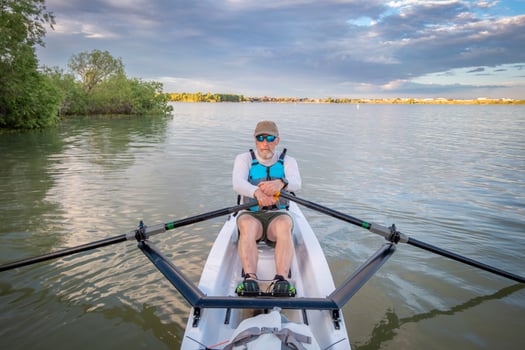 senior man in a rowing shell on a calm lake in Colorado in summer scenery photo