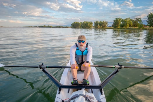 senior man in a rowing shell on a calm lake in Colorado in summer scenery photo