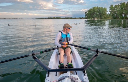 senior man in a rowing shell and Canadian geese on a calm lake in Colorado in summer scenery photo