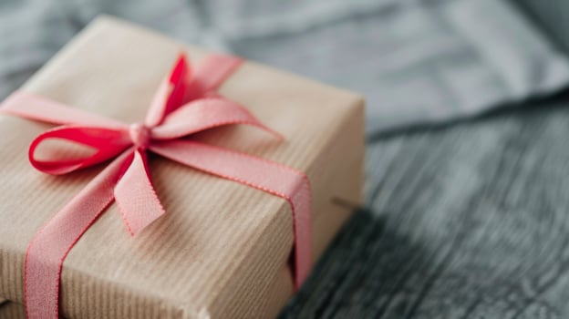 Gift Wrapped in Craft Paper With Pink Ribbon on Wooden Table photo