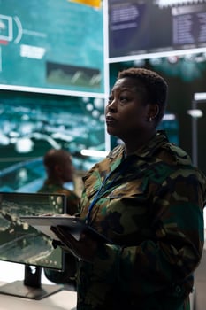 Woman recruit checking all surveillance footage from satellite CCTV, collecting important information to aid infantry unit in the field. Operating on a big screen in federal agency power base. photo