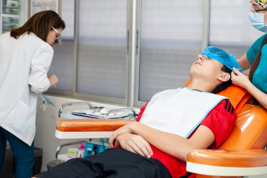Young male patient being prepared for a skin lesion removal procedure. Dermatologist carrying out a removal of benign skin lesion on the face of a young male patient. photo
