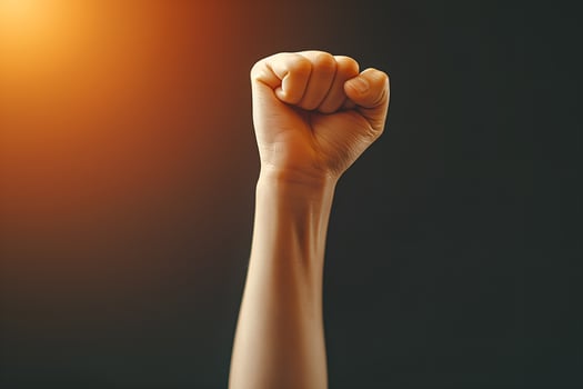 Close-up on fist raised up in the air on studio background photo
