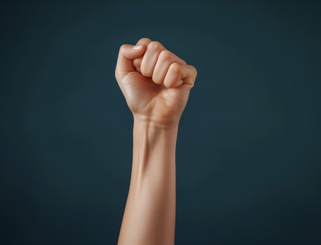 Close-up on fist raised up in the air on studio background photo