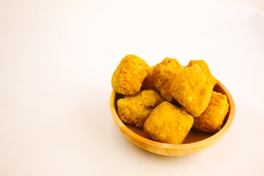 Tahu goreng cripsy, or crispy fried tofu, is one type of snack in Indonesia on wood plate isolated on white background. Perfect for recipe, article, catalogue, commercial, or any cooking contents photo