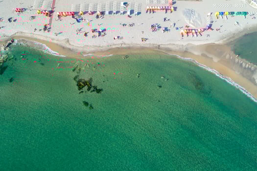 Aerial view of sandy beach with colorful umbrellas, swimming people in sea bay with transparent blue water at sunny day in summer. photo