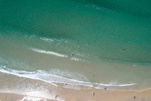 overhead aerial view of a beach with people enjoying the summer, bathing in the sea. photo