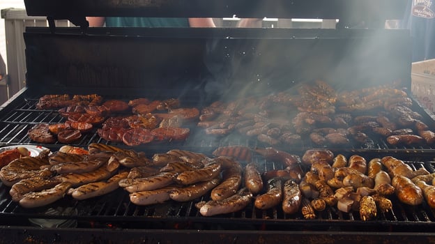 Assorted sausages and meats grilling on a barbecue with smoke rising photo