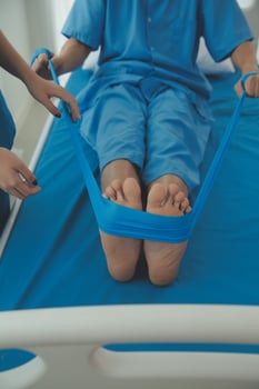 Professional orthopedist examining the little patient's leg in the clinic. Patient at the physiotherapy doing physical exercises with his therapist photo