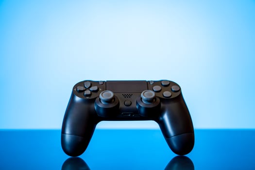 modern black gamepad on a glossy surface and a glowing blue photo