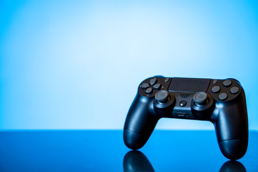 modern black gamepad on a glossy surface and a glowing blue photo