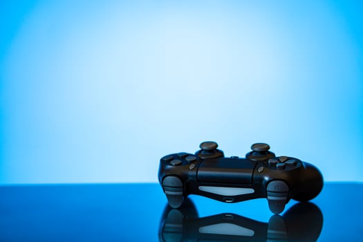 modern black gamepad on a glossy surface and a glowing blue photo