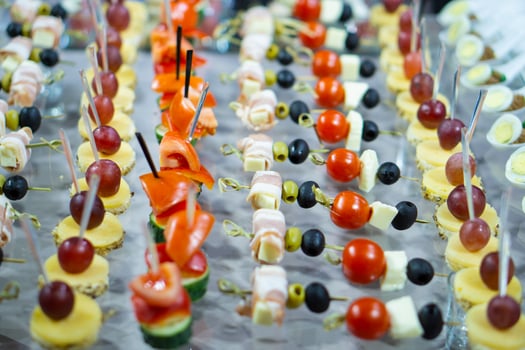 A variety of snacks and canapes are laid out on a glass table. Wickedly designed and laid out food. Holiday catering. Light back. photo