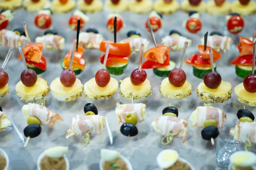 A variety of snacks and canapes are laid out on a glass table. Wickedly designed and laid out food. Holiday catering. Light back. photo