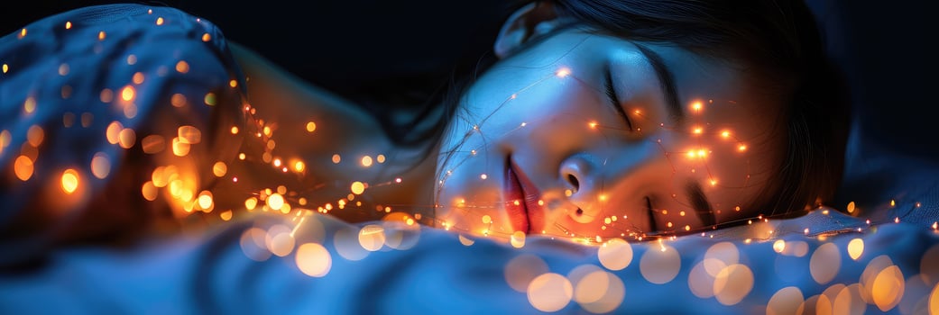 A woman sleeps in bed with Christmas lights on her face photo
