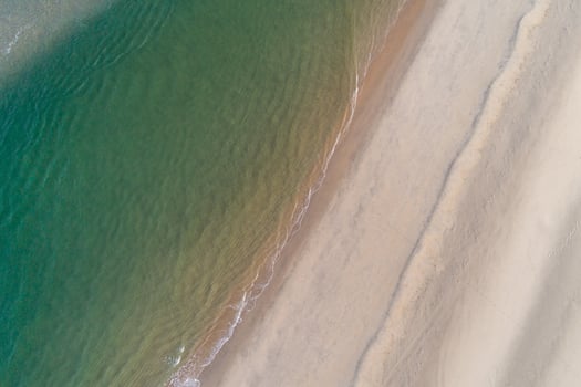 aerial drone view of the shore of a beach at sunrise in summertime photo