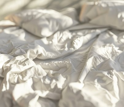 Cozy modern bedroom with crumpled white bedding in afternoon light photo