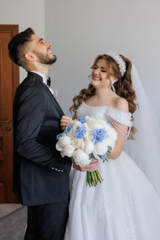A bride and groom are smiling at the camera. The bride is holding a bouquet of flowers and the groom is holding a bouquet of flowers photo