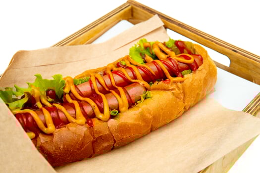 Hot dog with salad and cucumbers with tomato ketchup and mustard on white background. Tasty and beautiful fast food on a light back. photo