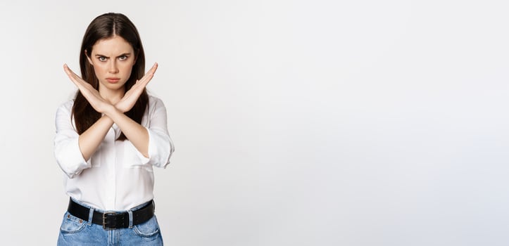 Serious woman showing stop sign, disagree, rejecting smth bad, standing over white background photo
