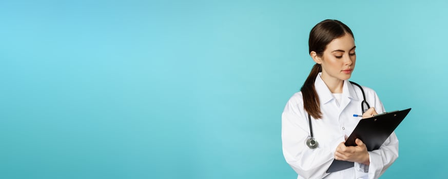 Image of professional woman doctor, physician with clipboard writing, listening patient at hospital clinic appointment, standing over torquoise background photo