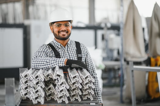 Operator of machine. Industrial worker indoors in factory. Young technician in white hard hat photo