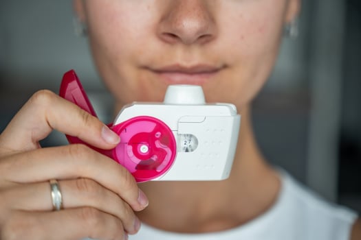 Close up view of woman using medicine dry powder inhaler for treatment asthma or COPD diseases. Pharmaceutical product is used to treat lung inflammation and prevent asthma attack. High quality photo