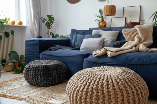 Modern blue sofa with knitted cushions in living room with big windows photo